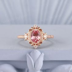 a pink diamond ring sitting on top of a white box