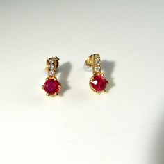 Here we have a gorgeous pair of natural earth mined vivid red ruby and sparkly diamond accent earrings crafted in solid 14K yellow gold. Together the pair weigh 3.2 grams approximately making them ideal for everyday wear. Each pretty earring measures approximately 1/2" long by 1/4" wide (12.6mm x 6.4mm). They are in lovely condition and are ready to gift or to wear. Each ruby measures respectively 5.14mm x 2.70mm and 5.08mm x 3.84mm. They weigh 0.52 carats and 0.84 carats. The diamond accents ea Single Ruby Earring In Red, Red Ruby Single Earring, Ruby Earrings With Brilliant Cut In Fine Jewelry Style, Ruby Brilliant Cut Fine Jewelry Earrings, Fine Jewelry Ruby Earrings With Brilliant Cut, Ruby Earrings Brilliant Cut Fine Jewelry, Yellow Gold Ruby Earrings With Brilliant Cut, Brilliant Cut Ruby Round Earrings, Red Diamond Earrings With Prong Setting