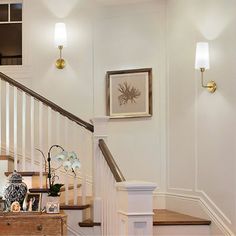 the stairs are white with wood handrails and framed pictures on each one wall