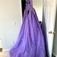 a purple ball gown hanging on a door