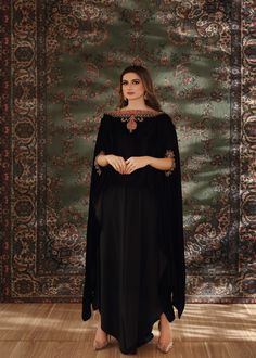 Black velvet cape style top handworked with dabka, tilla and zardozi on the neckline and sleeves. Paired with black flared pants to complete the chic look. Evening Dresses With Resham Embroidery And Cape Sleeves, Black Palazzo Set For Evening Eid, Black Evening Palazzo Set For Eid, Black Palazzo Set For Evening Eid Festival, Evening Kaftan With Dupatta, Elegant Kurta With Zari Work And Cape Sleeves, Black Embellished Palazzo Set For Eid, Evening Embellished Black Palazzo Set, Black Embellished Palazzo Set For Evening