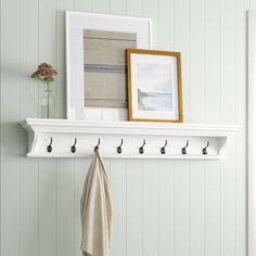 a coat rack with hooks on it next to a white wall and a framed photograph