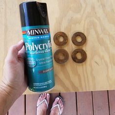 a person holding a spray bottle next to some donuts on a wooden table with other items