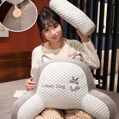 a woman sitting on top of a bed holding up an animal shaped pillow with the words lovely dog written on it