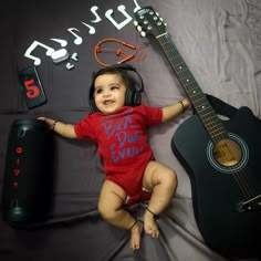 a baby is laying next to a guitar and headphones