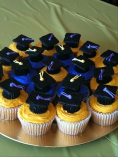 cupcakes decorated with graduation caps and tassels on a gold platter