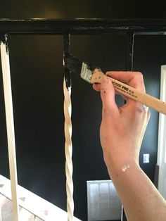 a person holding a paintbrush in their left hand and painting the ceiling with black paint