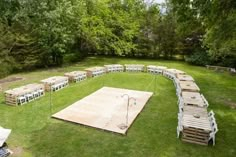 a large wooden dance floor in the middle of a grassy area with chairs around it