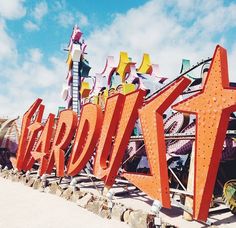 a large neon sign sitting on the side of a road next to a roller coaster