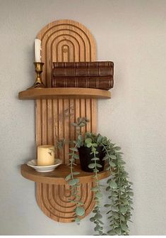 a wooden shelf with books and plants on it next to a wall mounted candle holder