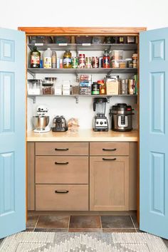 a kitchen with blue doors opened to reveal the pantry and coffee maker on the counter