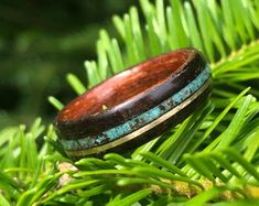 a wooden ring sitting on top of a green tree branch in the forest with lots of leaves around it