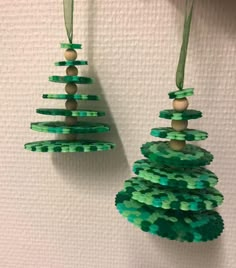 two christmas trees made out of beads hanging from strings on a wall next to each other