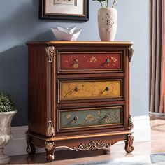 a wooden dresser with three drawers painted in different colors and flowers on the bottom drawer