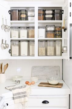 an organized kitchen with white cabinets and drawers