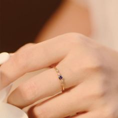 a woman's hand with a gold ring and blue sapphires on her finger