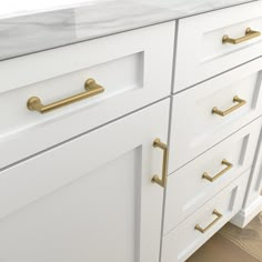 a white and gold bathroom vanity with marble counter tops, brass handles and drawers on the bottom