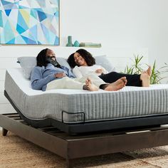 two people laying on top of a bed in a room