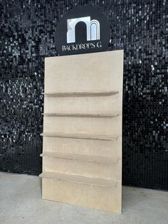 a wooden display case sitting in front of a black and white mosaic wall with the words harro's g on it