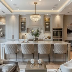 an elegant kitchen with marble counter tops and white cabinets, along with gray upholstered chairs