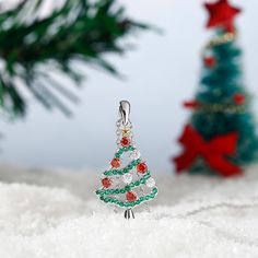 Celebrate the season any time of year with this shimmering Christmas tree pendant. Beautifully handcrafted in sterling silver, this pendant features an evergreen - decorated with alluring enhanced green stones, red stones, and white stones - that features a gold-tone silver star on the top. A festive look that will go with any outfit, this Christmas tree necklace will be a lovely gift for her this season!Carat Weight: 0.89 ctStone Size: 2.4,1,1.2 mmStone Type: Jeulia® StoneNumber of Stones: 44 S Silver Christmas Holiday Jewelry, Christmas Holiday Green Jewelry, Green Christmas Holiday Jewelry, Silver Jewelry For New Year Holiday, Green Sparkling Stones Necklace For Gift, Silver Christmas Pendant Necklace, Green Christmas Jewelry For Festive Occasion, Green Festive Jewelry For New Year, Sterling Silver Necklaces For Christmas