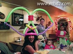 a group of people sitting around a table with food on top of it and balloons hanging from the ceiling