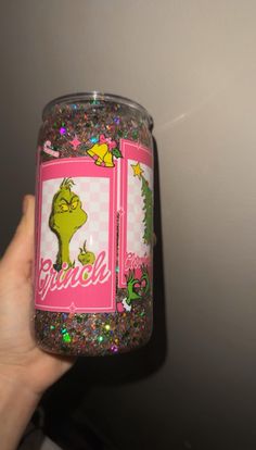 a hand holding up a pink and green glittered jar with the words grin on it