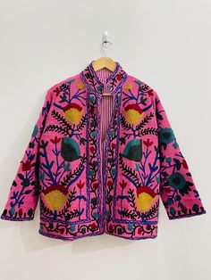 Experience the ultimate blend of luxury and bohemian style with our Suzani Hand-Embroidered Boho Jacket in vibrant Pink/Yellow hues. This exquisite piece, meticulously handcrafted, features intricate Suzani embroidery that radiates elegance and artistic charm. Made from premium Cotton canvas, this jacket is designed to provide both warmth and style, making it the perfect addition to your winter/ summer wardrobe. Ideal for both men and women, this versatile jacket is not just a piece of clothing Traditional Pink Nehru Jacket For Spring, Bohemian Floral Embroidered Cardigan, Bohemian Outerwear With Chikankari Embroidery For Spring, Traditional Pink Nehru Jacket With Floral Embroidery, Pink Bohemian Outerwear For Festival, Pink Festival Outerwear, Bohemian Nehru Jacket With Floral Embroidery For Festivals, Spring Folk Outerwear With Chikankari Embroidery, Bohemian Nehru Jacket With Intricate Embroidery