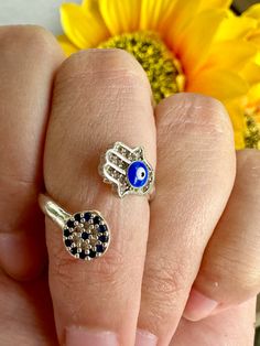 a woman's hand holding two rings with an evil eye on it and a sunflower