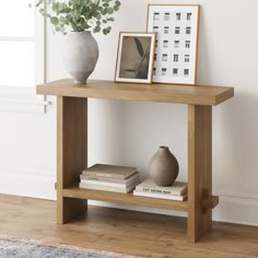 a wooden table topped with books next to a vase and framed pictures on top of it