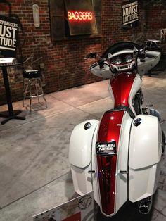 a red and white motorcycle parked in front of a brick wall with signs on it