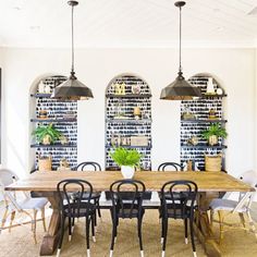 a dining room table surrounded by chairs and potted plants