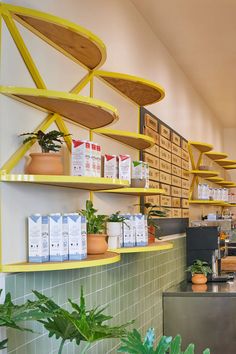 the interior of a coffee shop with shelves and plants