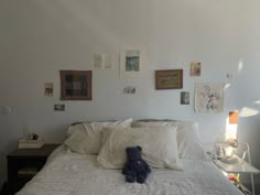 a teddy bear sitting on top of a bed in a room with white sheets and pillows