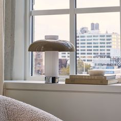 a lamp sitting on top of a window sill next to a book and cup