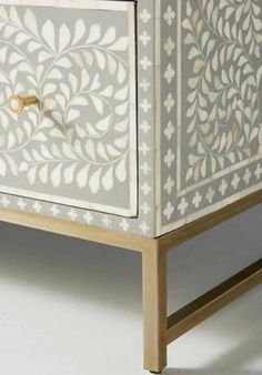 an ornate white cabinet with gold handles on the top and bottom, in front of a white background