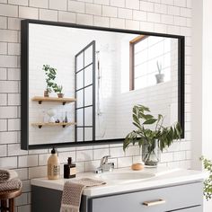 a bathroom with white tile and black framed mirror