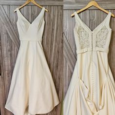 two dresses hanging on a wooden wall next to each other, one in white and the other in beige