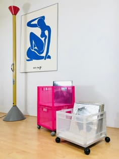 three plastic storage containers sitting on top of a hard wood floor next to a lamp