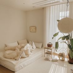 a living room filled with lots of white furniture and plants on top of the floor