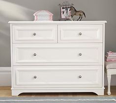 a white dresser sitting in a bedroom next to a wall with a horse on it