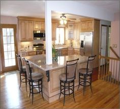 a kitchen with an island and four stools in the center, along with stainless steel appliances