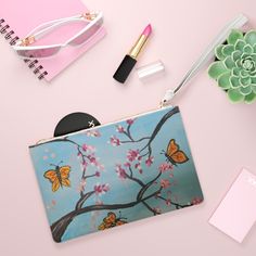 a purse with butterflies on it next to a plant and other items that include lipstick