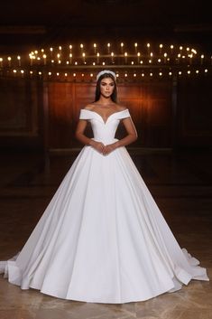 a woman in a white wedding dress posing for the camera with her hands on her hips