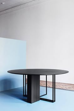 a black table sitting on top of a blue floor next to a white and gray wall