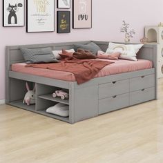 a bedroom with pink walls and pictures on the wall above the bed that has drawers underneath it