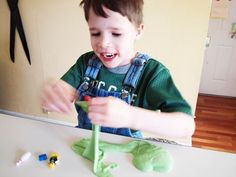 a little boy that is standing in front of a table with some toy animals on it