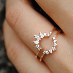 a woman's hand wearing a gold ring with pear shaped diamonds on the band