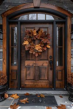 a front door with a wreath on it and autumn leaves in the ground next to it