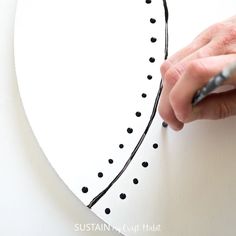 someone is drawing a heart on a piece of paper with black dots in the shape of a half circle